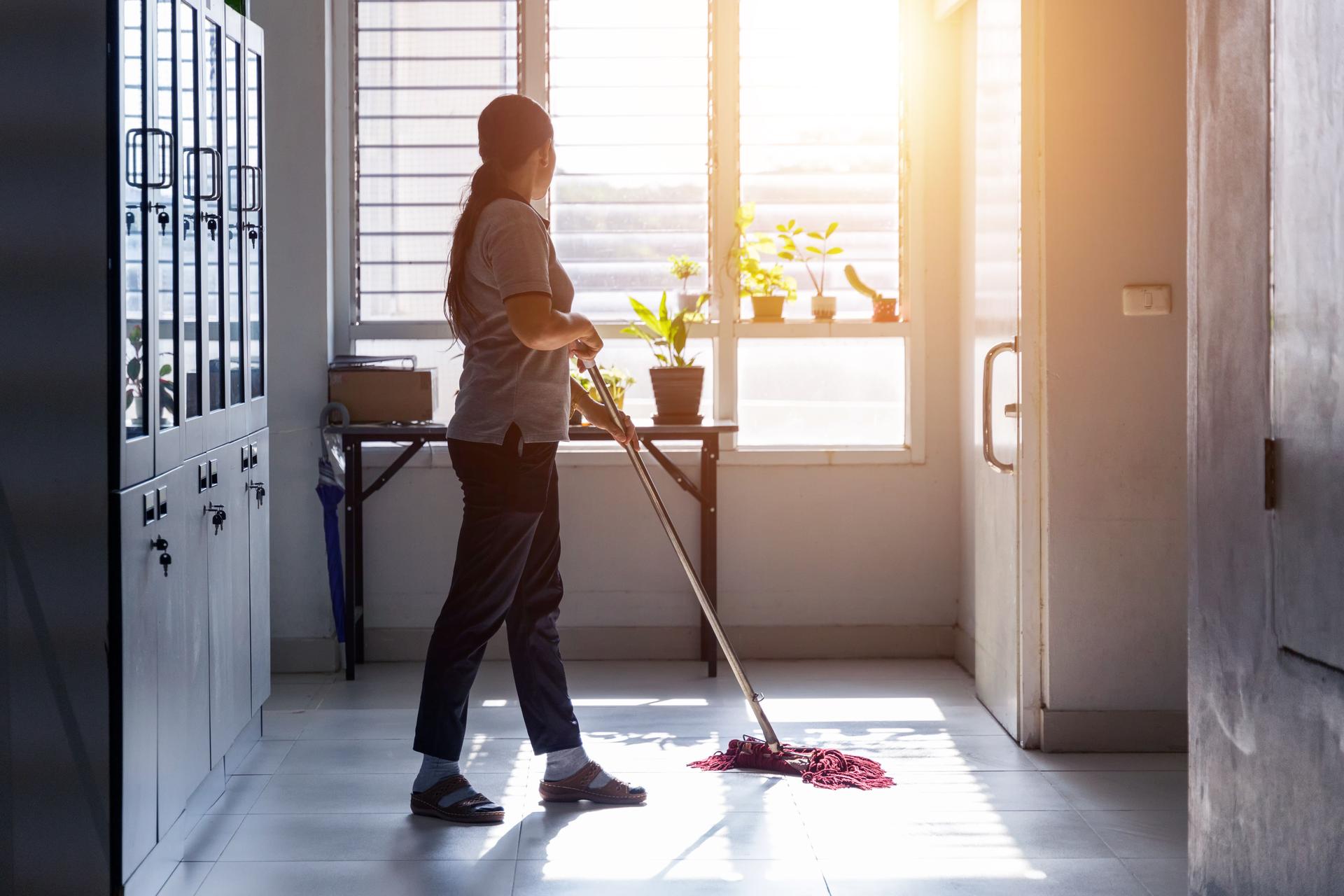 Janitor woman mopping floor in hallway office building or walkway after school or classroom with blank copy space.